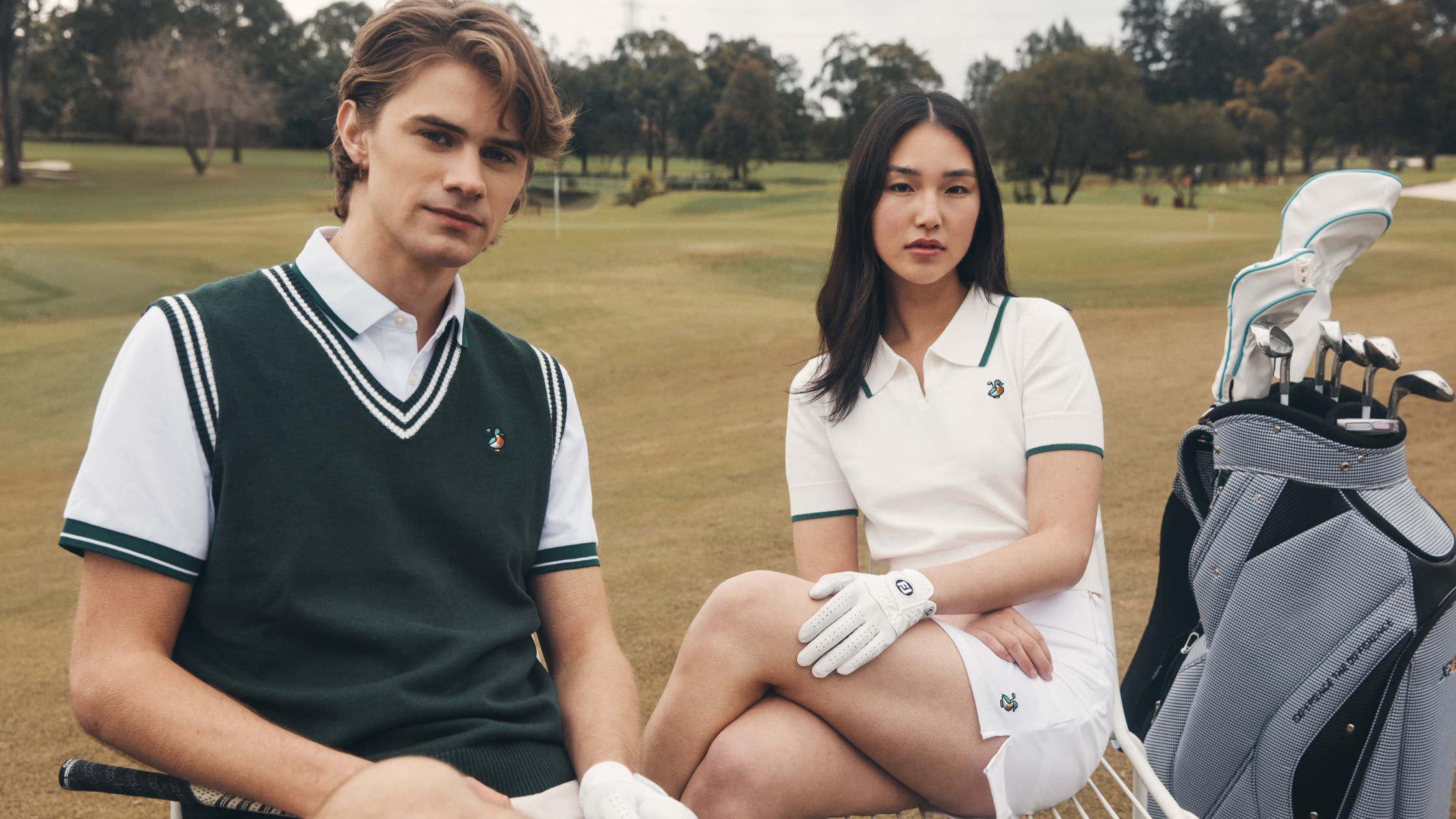 Two people on a golf course with golf bags and clubs.