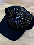 Black cap with textured back and brand logo on a wooden surface