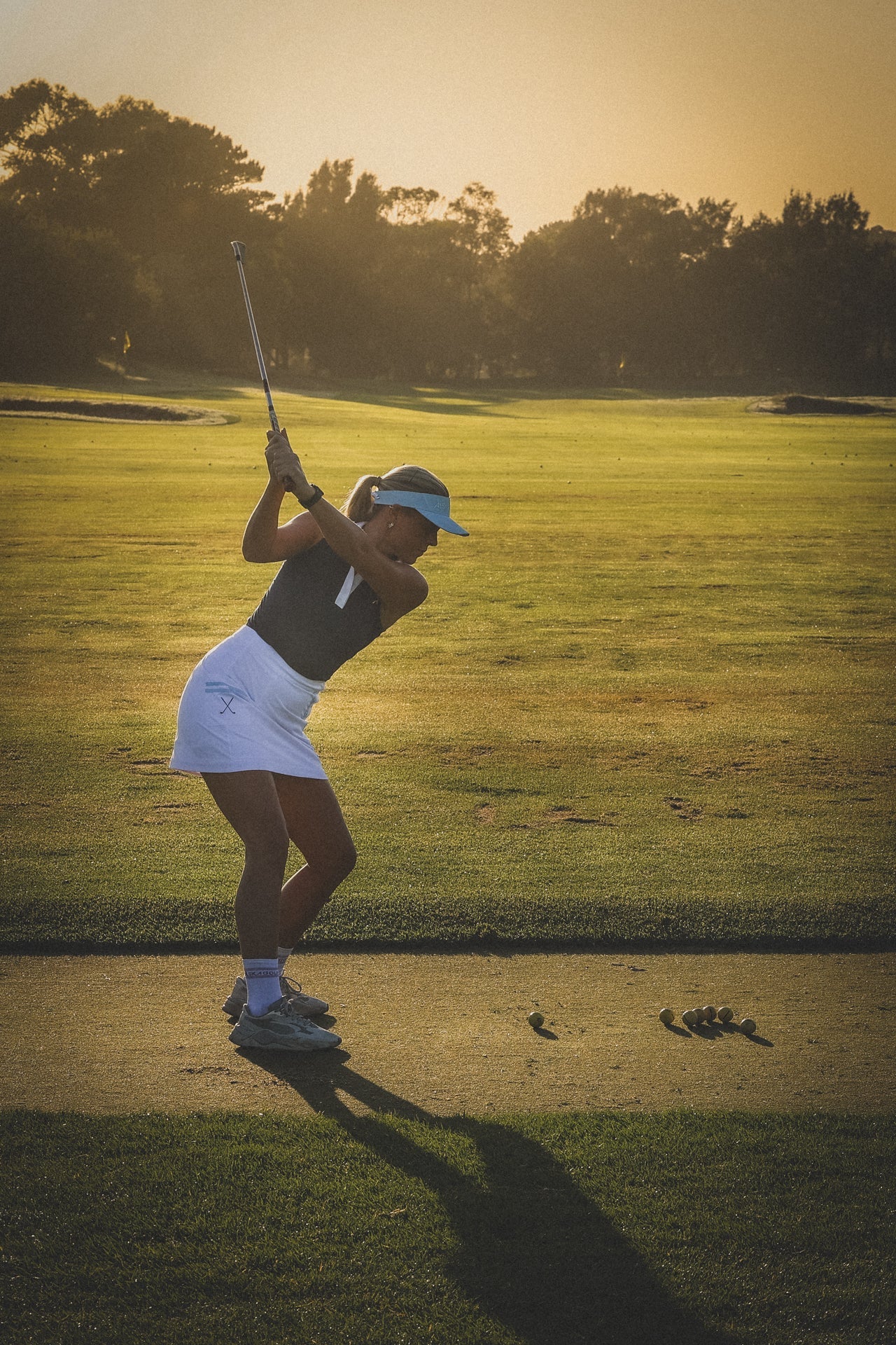 Woman playing golf on a well-maintained course with trees in the background