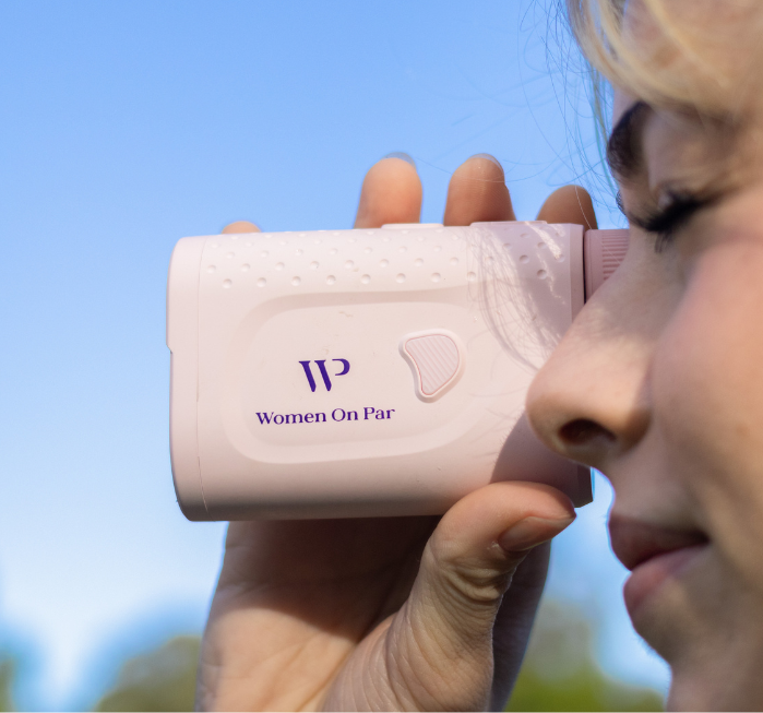 Lady holding a ladies pink rangefinder with 'Women On Par' branding against a blue sky.