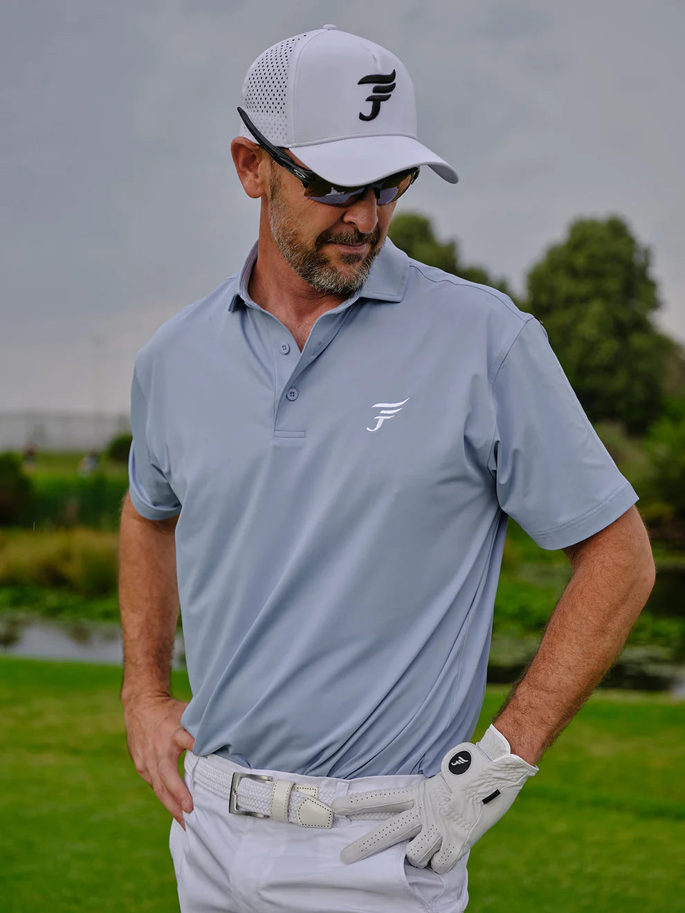 Man in golf attire with a cap and glove on a golf course