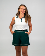 Woman wearing a white sleeveless shirt with green trim and green shorts on a gray background